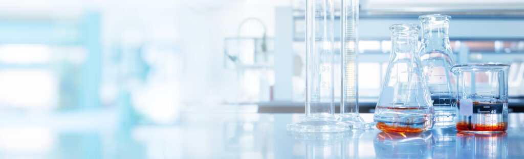 water and orange solution in glass flask and cylinder in soft blue light reseach medical science laboratory banner background