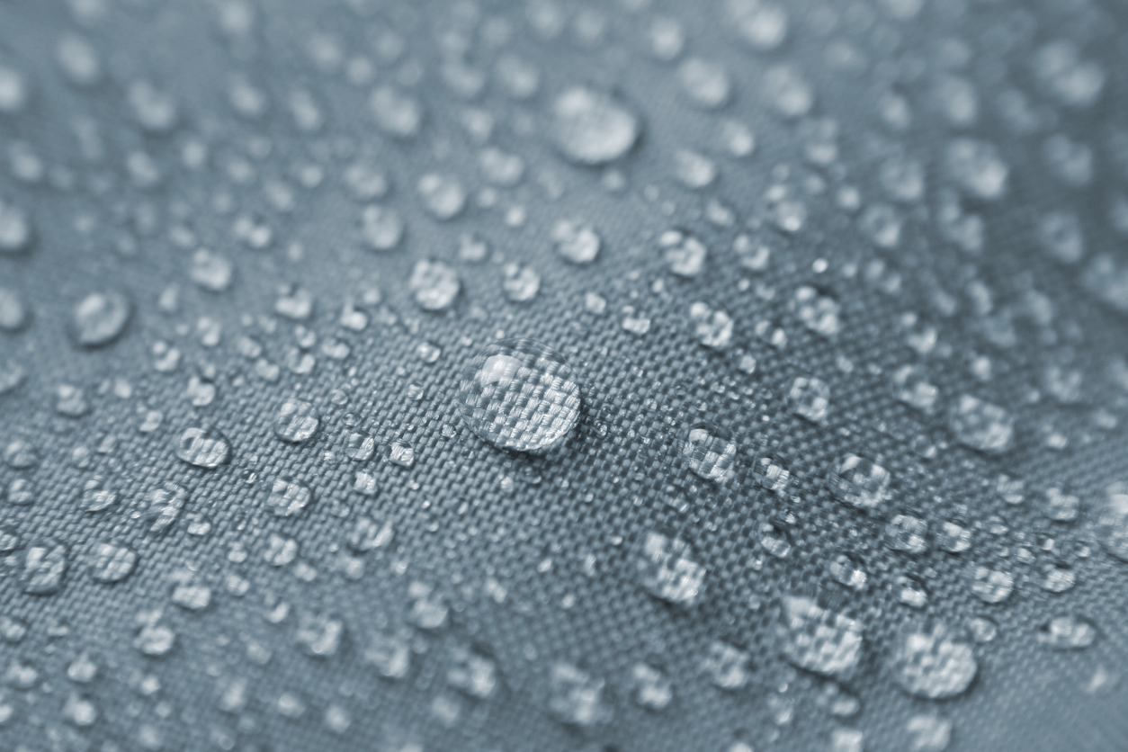 Macro shot of rain drops pearling on waterproof nylon jacket. Short DOF. Zoom in on the largest droplet to appreciate the details.