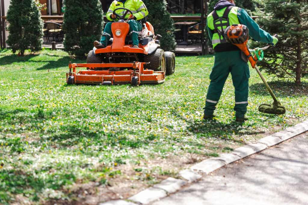 Professional landscapers mowing lawn with a mower and trimming edges - symbolizing small engine emissions