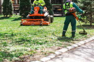 Professional landscapers mowing lawn with a mower and trimming edges - symbolizing small engine emissions