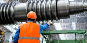 Chemical engineer supervising metal pipes, highlighting the role of monitoring catalyst deactivation in industrial processes.